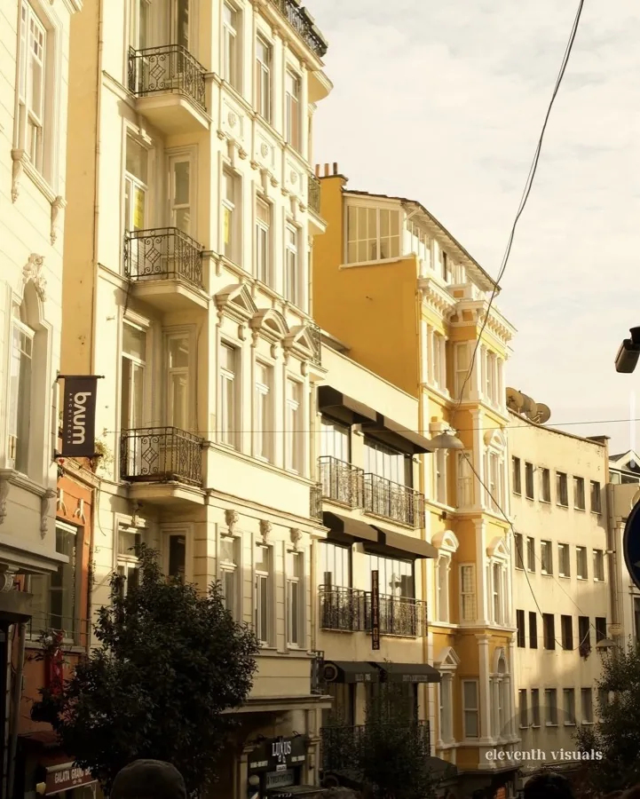 Sunlit historic street facades in pale stone and yellow above the Galata shops.